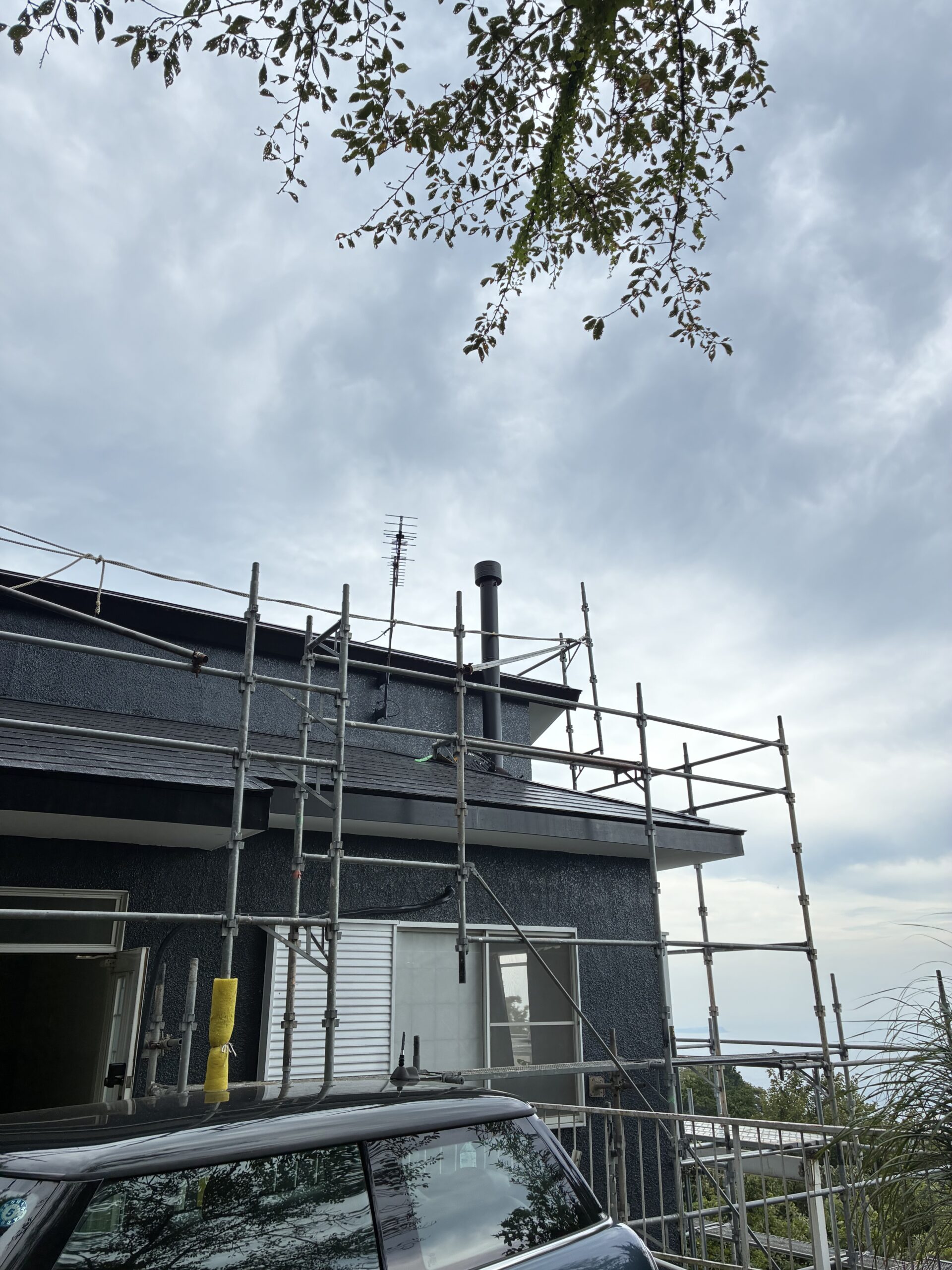 足場を組んだ住宅の屋根と煙突